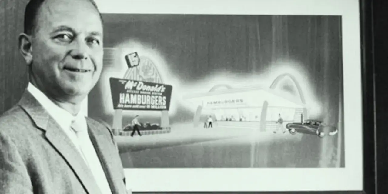 Ray Kroc, który wymyślił McDonald's, stoi obok obrazu przedstawiającego pierwszy lokal.