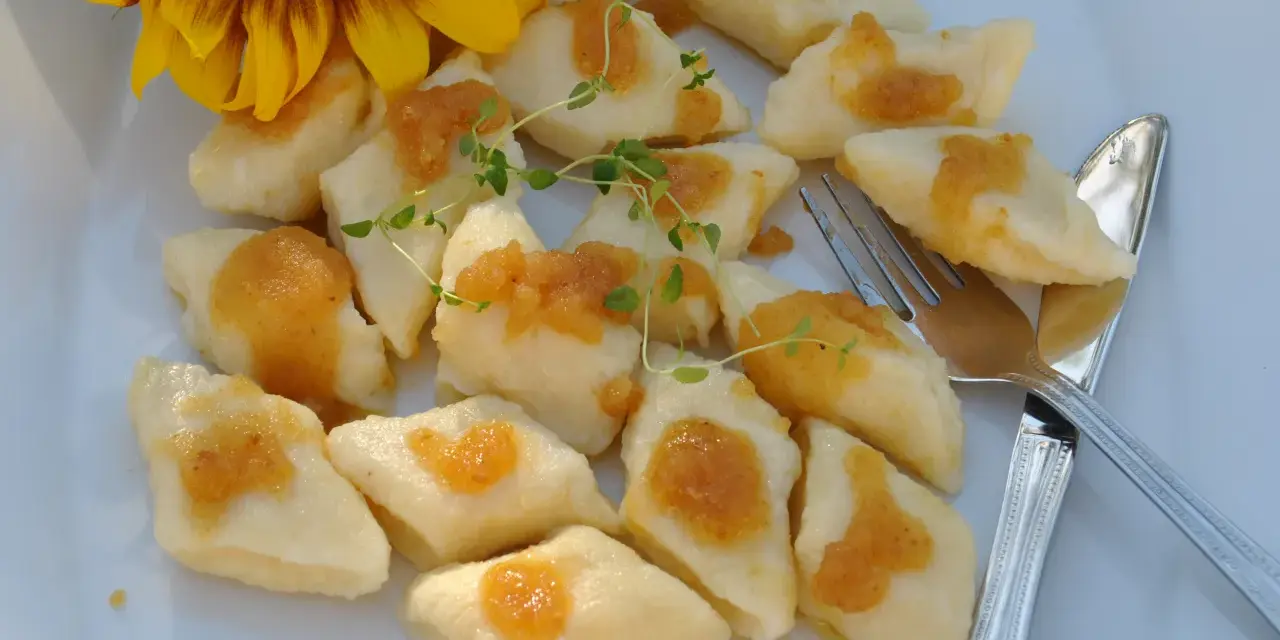 Pyszne, leniwe pierogi z sosem i gałązką tymianku, obok słonecznik.
