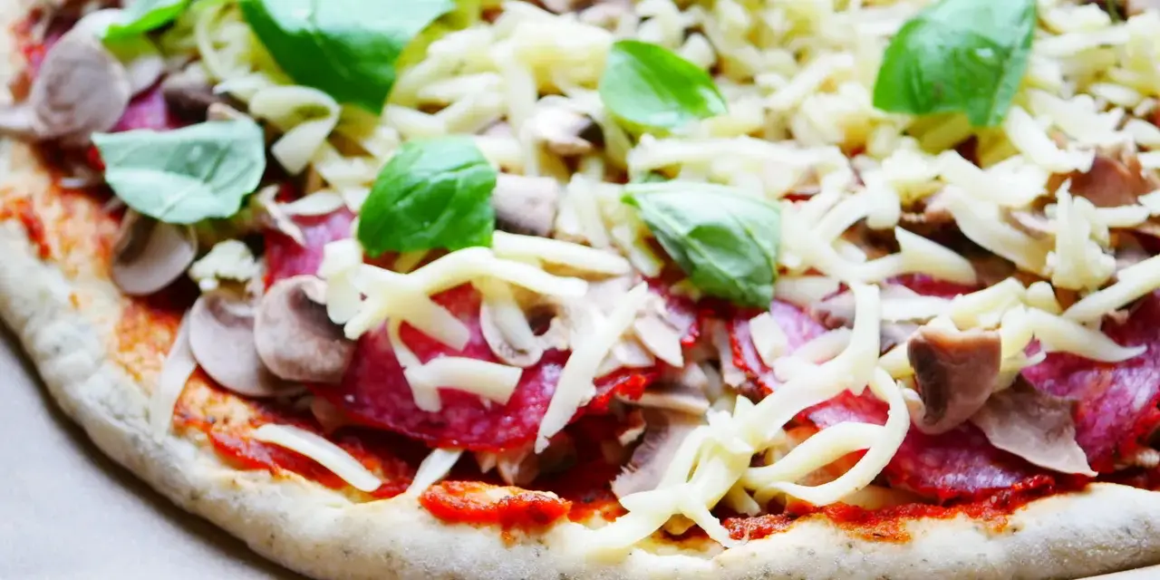 Gotowy do pieczenia przepis na ciasto do pizzy: sos pomidorowy, salami, pieczarki, ser i świeża bazylia.
