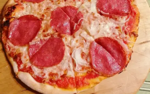 Pyszna pizza salami z serem i cebulą, idealna na szybki obiad.