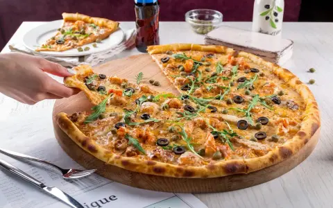 Pyszna pizza z krewetkami, oliwkami i kaparami, serwowana w klimatycznej **pizzerii Stare Miasto**. Idealna na wspólny posiłek.
