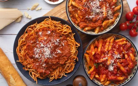 Pyszny obiad bez mięsa: spaghetti i penne w sosie pomidorowym, posypane parmezanem. Idealne dla wegetarian!