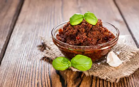 Miseczka pełna aromatycznego, czerwonego pesto z bazylią i czosnkiem, gotowa do podania.