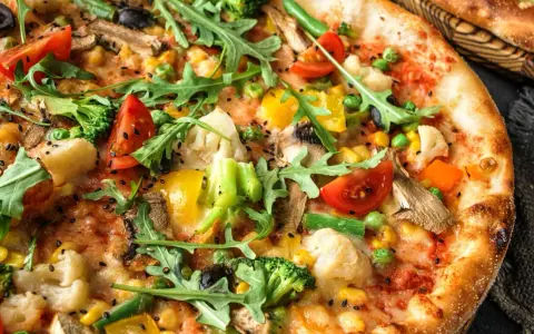 Pyszna pizza bez mięsa z brokułami, pomidorkami, kukurydzą, papryką i rukolą.