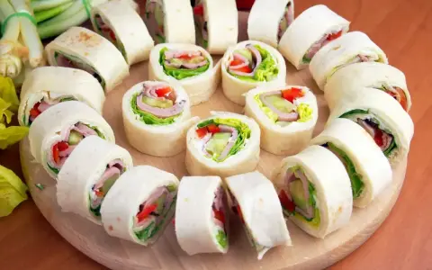 Szybkie przekąski z tortilli na zimno: roladki z szynką, serem, warzywami i sałatą. Idealne na imprezę lub lunch.