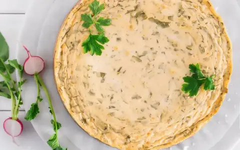 Pyszny sernik na zimno z wiaderka, ozdobiony natką pietruszki. Idealny na letnie dni, a przepisy na niego znajdziesz w internecie.