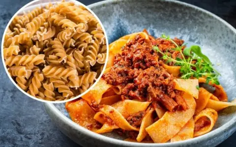 Pyszny makaron na redukcji z sosem bolognese. Widać też surowy makaron fusilli, idealny do zdrowych posiłków.