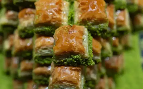 Słodka baklava, co to jest? Warstwy ciasta filo, orzechów i syropu, posypane zielonymi pistacjami. Pyszny deser!