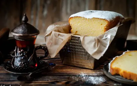 Wilgotna babka w keksówce, oprószona cukrem pudrem, obok paruje herbata w orientalnej filiżance. Idealny deser na chłodne popołudnie.