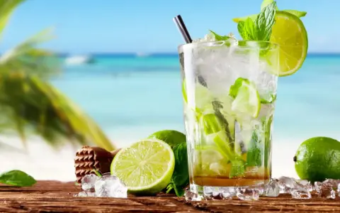 Orzeźwiający mojito na plaży, z limonkami i miętą, w tle błękitne morze i palmy. Idealny na upalny dzień.