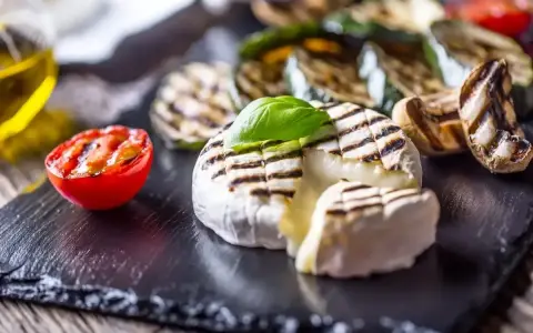 Pyszny camembert z grilla, z rumianymi paskami, podany z grillowanymi warzywami i pomidorkiem. Idealny na letnie wieczory.