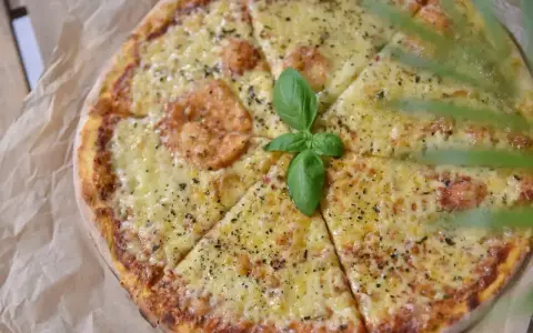 Pyszna pizza z roztopionym serem, idealna na wieczór. Zastanawiasz się, jaki ser do pizzy wybrać? Ten wygląda obłędnie!
