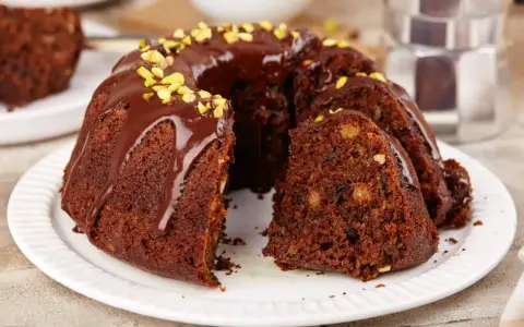 Wilgotna babka czekoladowa z orzechami, polana polewą i posypana pistacjami. Idealna na szybki deser.