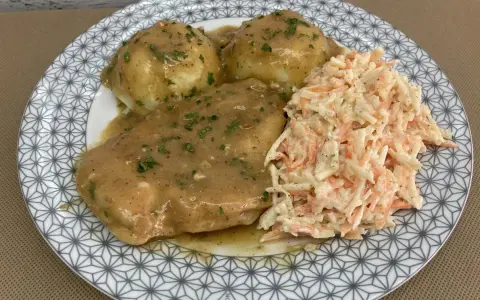 Pyszna pierś z kurczaka w sosie własnym, podana z ziemniakami i surówką z marchewki i kapusty.