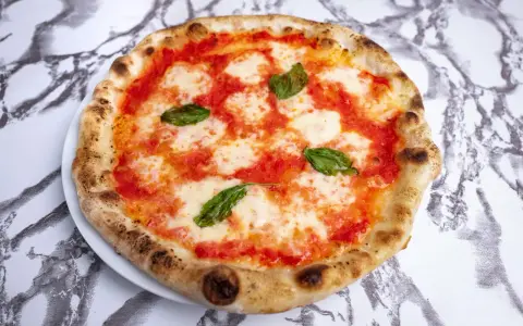Pyszne ciasto na pizzę neapolitańską z sosem pomidorowym, mozzarellą i bazylią. Idealna na szybki lunch.
