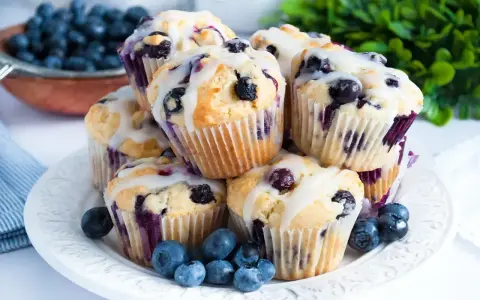 Wilgotne i puszyste muffinki z jagodami, polane lukrem. Idealne na śniadanie lub deser.