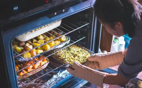 Ktoś wkłada do piekarnika naczynie z zapiekanką. W środku pieką się ziemniaki i marchewka. Ciekawe, podgrzewanie w piekarniku ile stopni?