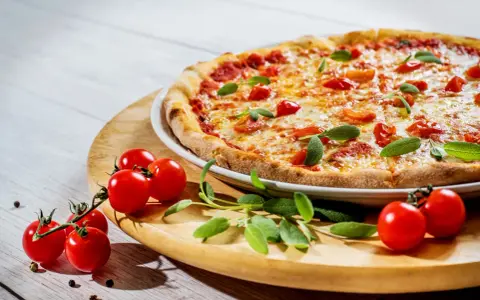Apetyczna pizza z pomidorkami i bazylią. Czy zastanawiałeś się, dlaczego pizza jest niezdrowa?
