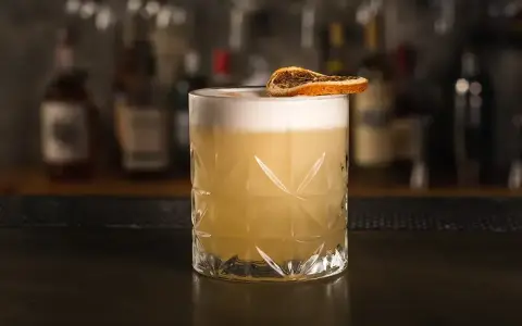 Klasyczny whisky sour przepis: orzeźwiający koktajl z pianką i plasterkiem suszonej pomarańczy. Idealny na każdą okazję.