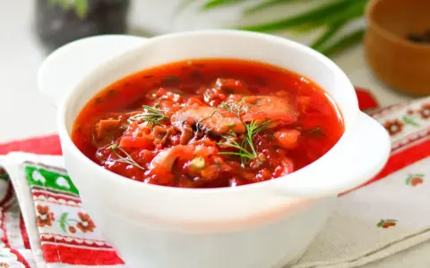 Aromaticzny barszcz ukraiński tradycyjny w białej miseczce, ozdobiony koperkiem. Idealny przepis na rozgrzewający obiad.