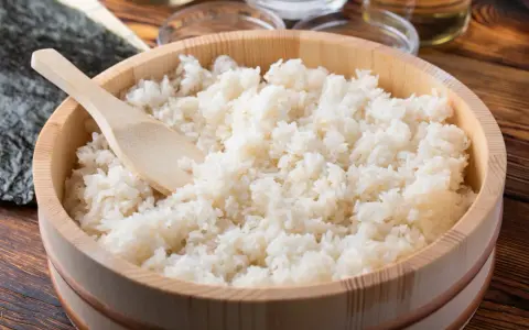 Idealny ryż do sushi, gotowy do przygotowania. Drewniana miska i łyżka sugerują tradycyjny sposób na to, jak ugotować ryż do sushi.