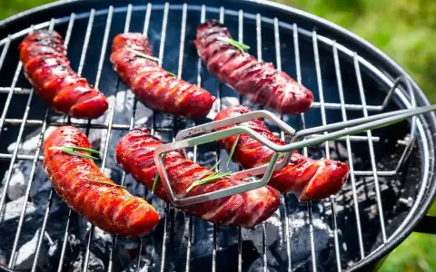 Aromatyczna kiełbasa z grilla, skwiercząca na węglu, z gałązkami rozmarynu. Idealna na letnie popołudnie.