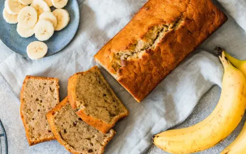 Pyszny, domowy chlebek bananowy – sprawdzony przepis na wilgotne ciasto. Obok kromki i plasterki banana.