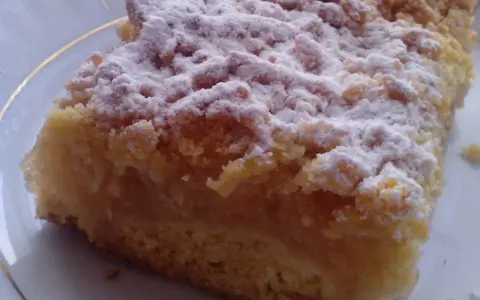 Kawałek puszystej szarlotki z kruszonką, posypanej cukrem pudrem. Idealna na podwieczorek, według najsmaczniejsza szarlotka przepis.