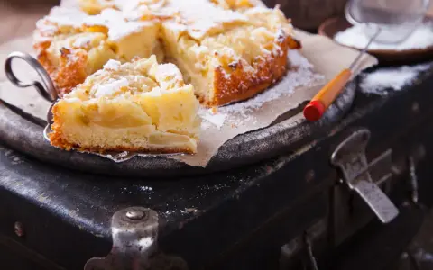 Pyszne, domowe ciasto z jabłkami, posypane cukrem pudrem, czeka na spróbowanie. Idealne na deser!