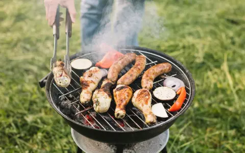 Pyszne kiełbaski i kurczak pieką się na grillu, a dym unosi się w powietrzu. Idealny sposób, jak rozpalić grilla i cieszyć się latem.