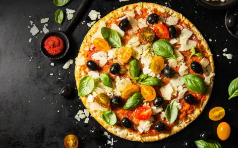 Pizza z pomidorkami, oliwkami i bazylią. Pomidorowe pesto to niezbędny dodatek smakowy włoskiej pizzy.