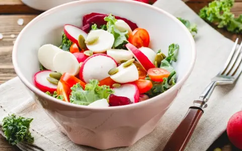 Świeża sałatka do grilla w 3 minuty: rzodkiewka, pomidorki, ser mozzarella i pestki dyni w misce.