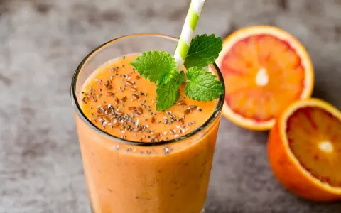 Pomarańczowy smoothie z nasionami chia i siemieniem lnianym, ozdobione miętą. Idealne na zdrowe śniadanie. Inspiracja na smoothie przepisy.