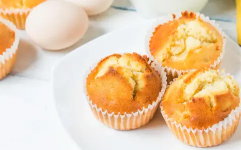 Złociste babeczki z airfryer na białym talerzu, obok jajka. Idealne na szybką przekąskę.