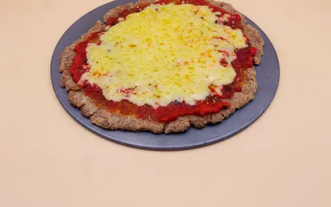Pizza z chleba tostowego z sosem pomidorowym i roztopionym serem na ciemnej tacy.