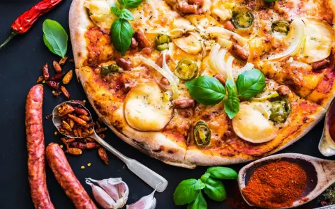 Apetyczna pizza z kiełbasą, cebulą i papryczkami jalapeño, otoczona składnikami.