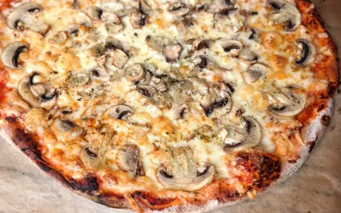 Pyszna pizza włoska z pieczarkami i ciągnącym serem. Idealny przepis na domową ucztę.