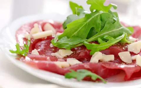 Cienkie plastry wołowiny z rukolą i parmezanem, polane pysznym sosem do carpaccio.