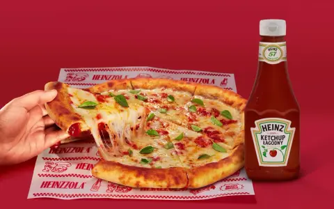 Ciepła pizza z ciągnącym serem i bazylią, obok butelka łagodnego ketchupu Heinz – idealny duet do każdego kęsa.