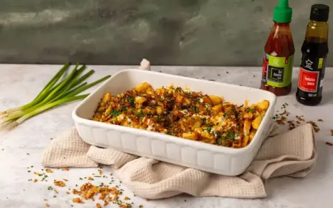 Pyszne frytki z chrupiącą posypką i sosem. Obok butelki sosu Sriracha i Tonkatsu, idealne do frytek.