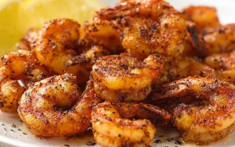 Pyszne krewetki z airfryer, przyprawione i lekko przypieczone, z plasterkiem cytryny w tle.