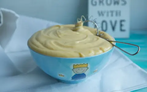 Gładki, kremowy krem patissiere w niebieskiej miseczce z małym królem. Idealny do deserów.