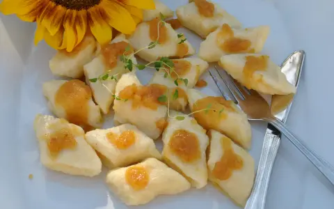 Pyszne, leniwe pierogi z sosem i gałązką tymianku, obok słonecznik.