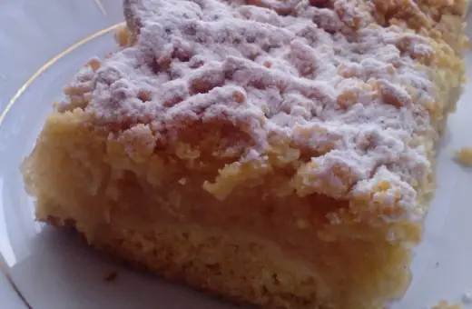 Kawałek puszystej szarlotki z kruszonką, posypanej cukrem pudrem. Idealna na podwieczorek, według najsmaczniejsza szarlotka przepis.