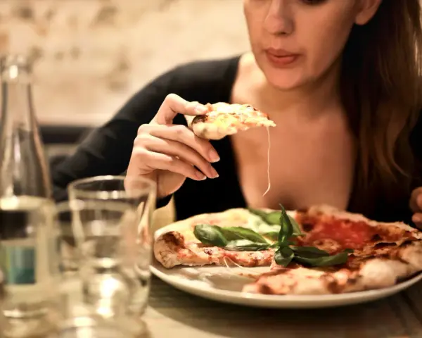 Smakowita pizza dla nas dwojga. Kobieta bierze kawałek, ciągnie się ser.