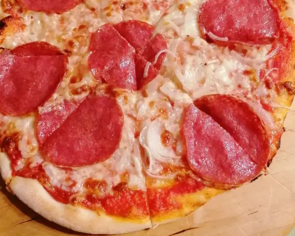 Pyszna pizza salami z serem i cebulą, idealna na szybki obiad.