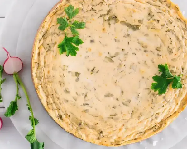 Pyszny sernik na zimno z wiaderka, ozdobiony natką pietruszki. Idealny na letnie dni, a przepisy na niego znajdziesz w internecie.