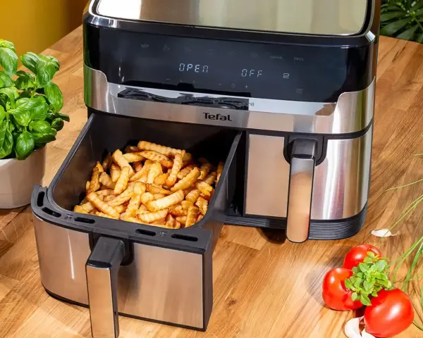 Frytki z frytkownicy beztłuszczowej Tefal, idealne do rankingu air fryer. Obok bazylia i pomidory.