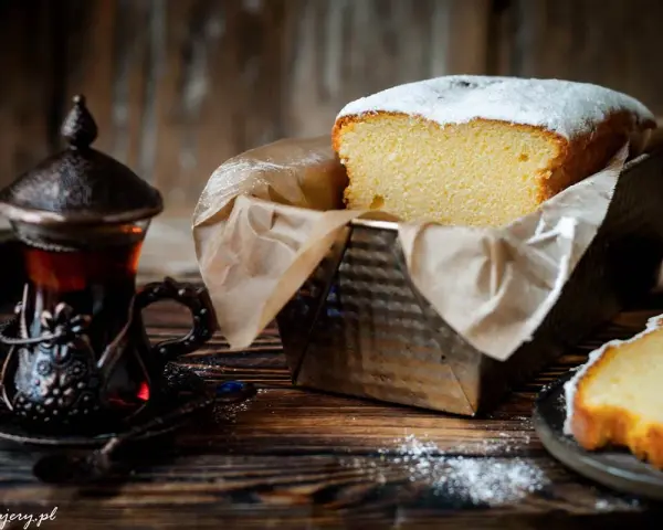 Wilgotna babka w keksówce, oprószona cukrem pudrem, obok paruje herbata w orientalnej filiżance. Idealny deser na chłodne popołudnie.