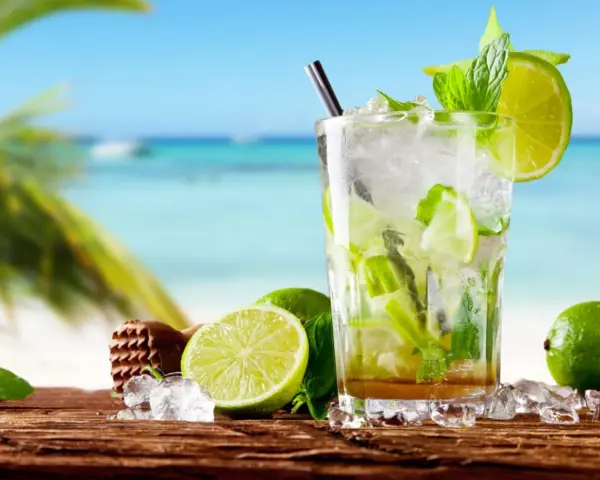 Orzeźwiający mojito na plaży, z limonkami i miętą, w tle błękitne morze i palmy. Idealny na upalny dzień.